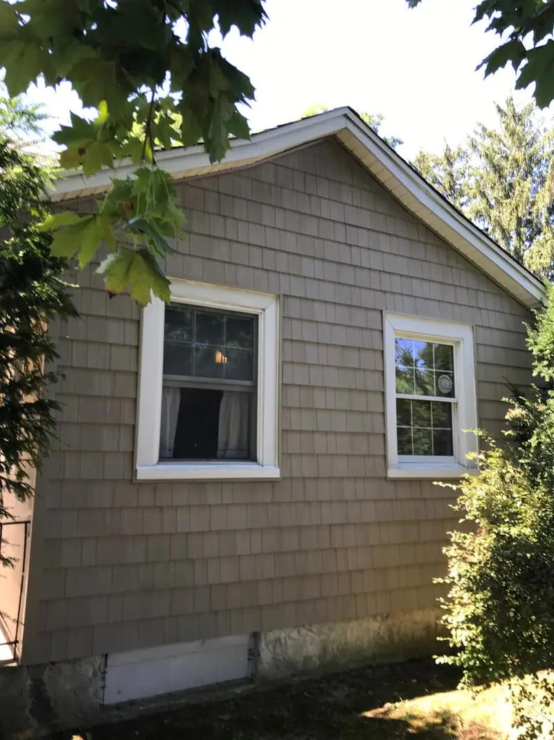 Side of a shingled cottage with white-trimmed windows, Lindenhurst, NY